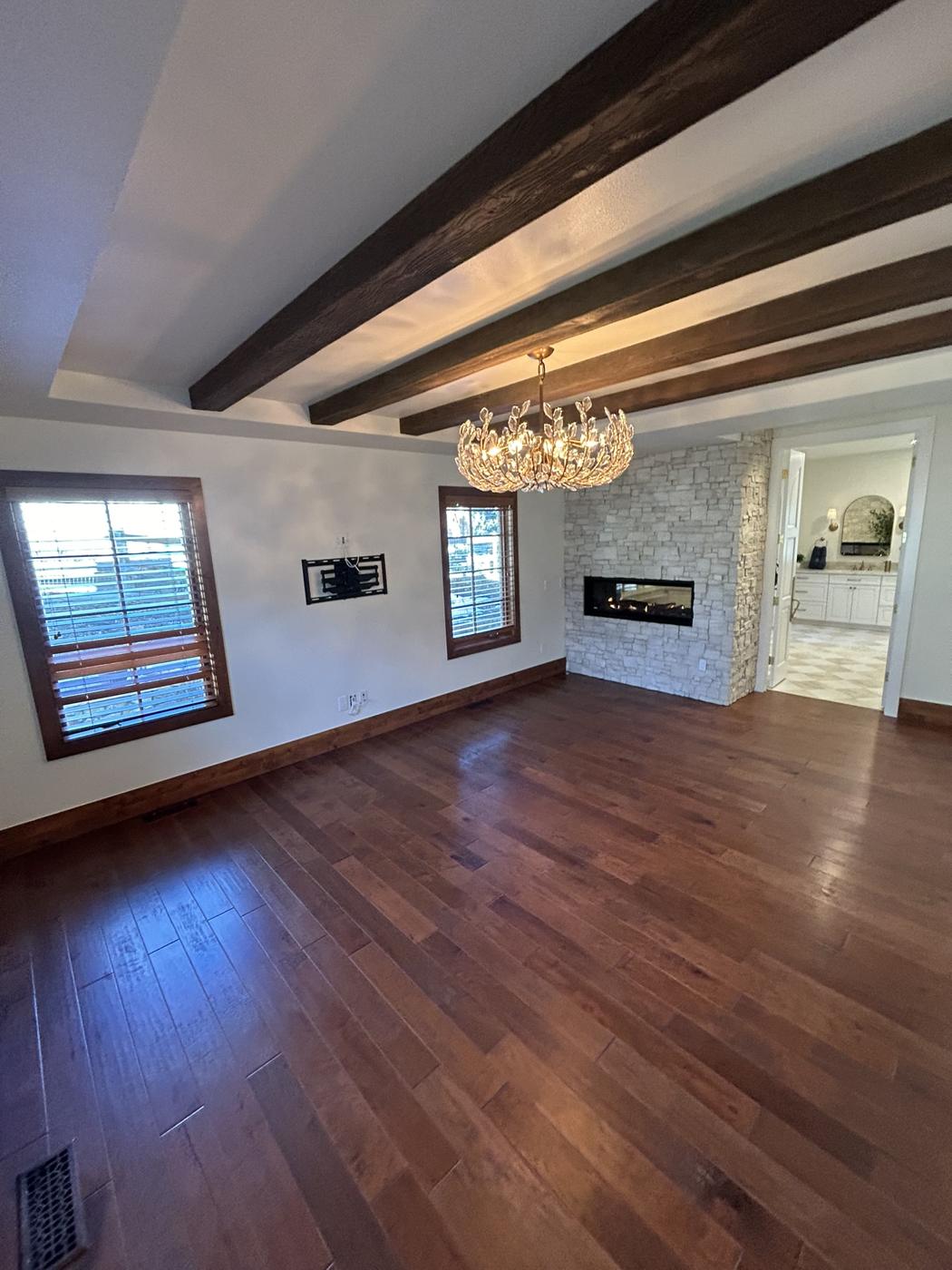 Bedroom after with hardwood floors and ceiling beams