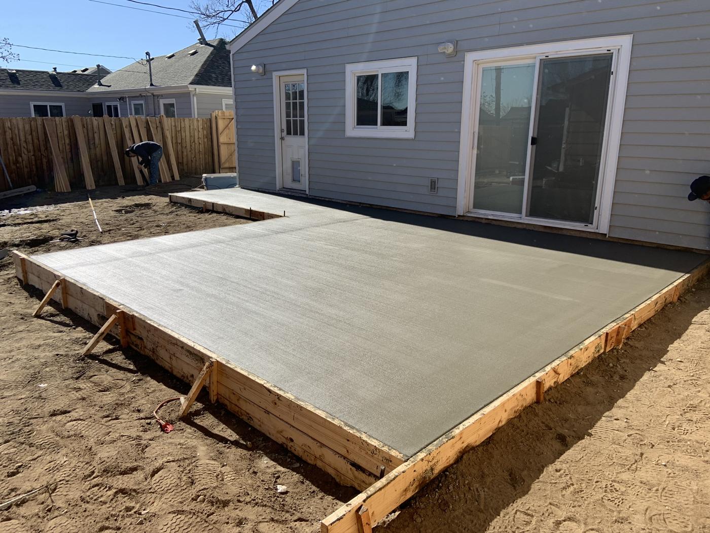 Freshly poured concrete patio behind a home
