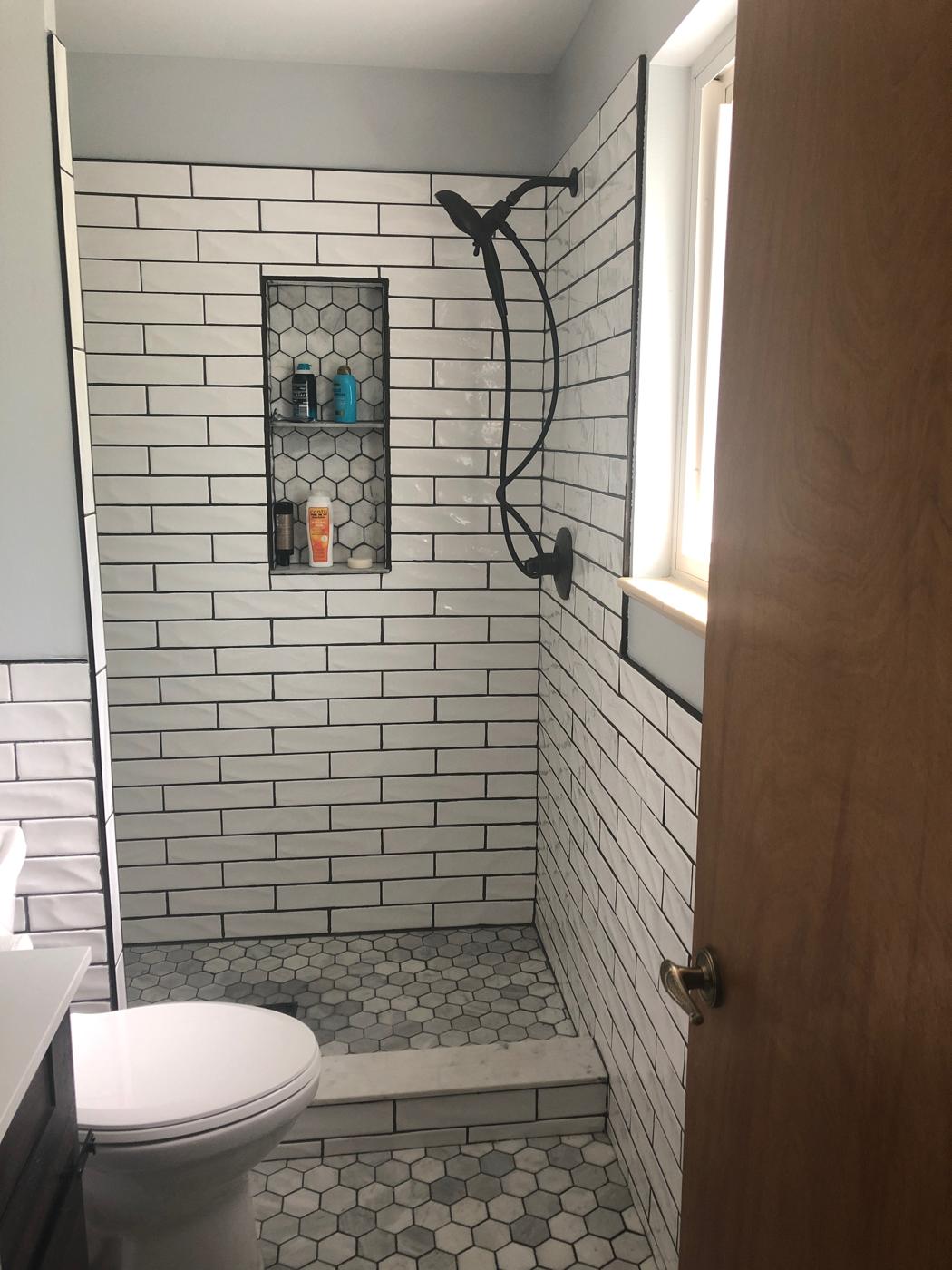 Subway tile shower with niche and patterned floor
